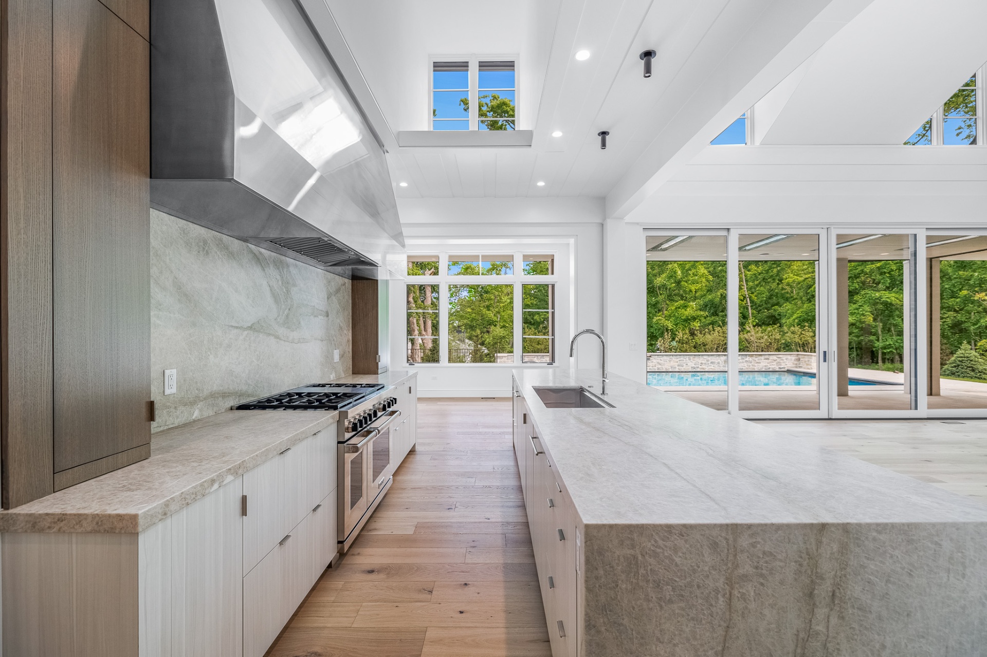 Chef's kitchen open to pool and forest